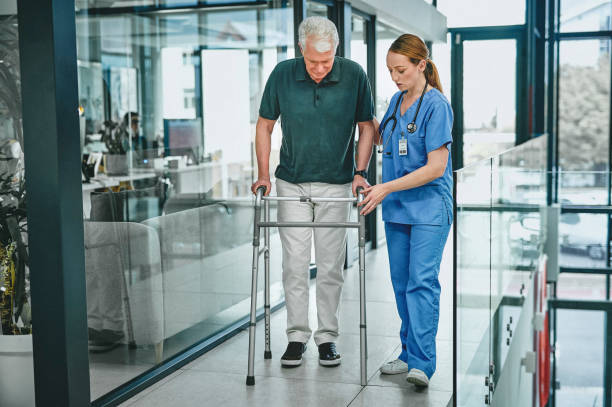 Shot of a young doctor helping her elderly patient with a walker stock photo
