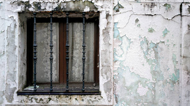 Santiago de Compostela old town, traditional stone house facade  painted white, peeling off, , retro style closed window, cast iron security bars. Galicia, Spain.