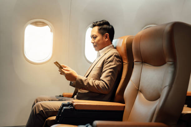 Businessman using smartphone while sitting in airplane stock photo