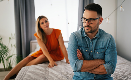 Sad pensive couple thinking of relationships problems sitting on sofa, conflicts in marriage, upset couple after fight dispute, making decision of breaking up get divorced