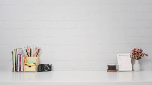 istock Stylish workplace with camera, coffee cup, picture frame and stationery on white table. 1390024943