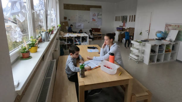 istock Boy drawing with his female teacher sitting in classroom 1390027467