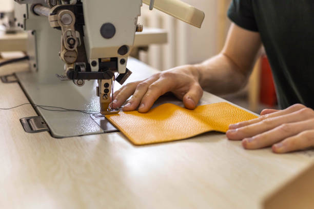 istock Close up craftsman hands sew stuff blank for wallet use sewing machine. Working at leather workshop 1390028850