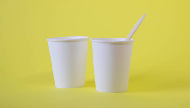 istock Two small white paper cups on a yellow background 1390032692