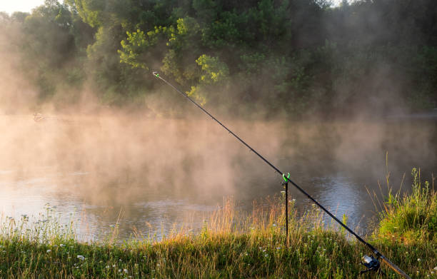 Silhouette of fisherman standing in the lake and catching the fish during sunrise