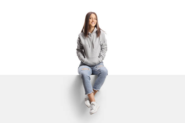istock Young female sitting on a blank board and looking at camera 1390035167