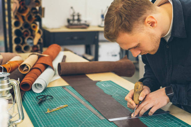 istock Male tanner making cutting scheme of bag working at leather workshop. Handcrafted creating 1390037383