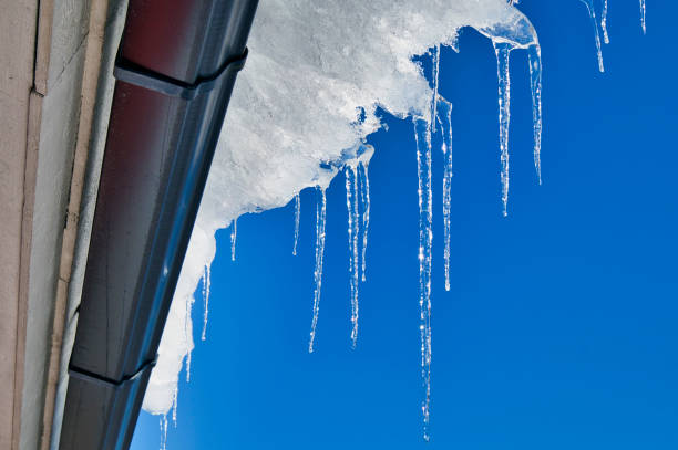 Close-up of shiny icicles on a roof gutter on a sunny day.