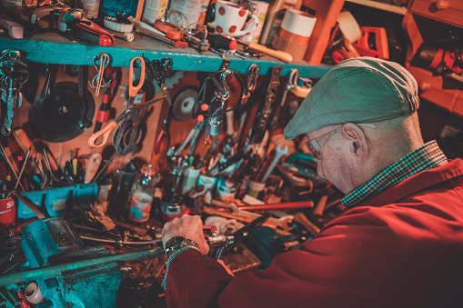 Senior having a hobby and fixing pipes at home the old way