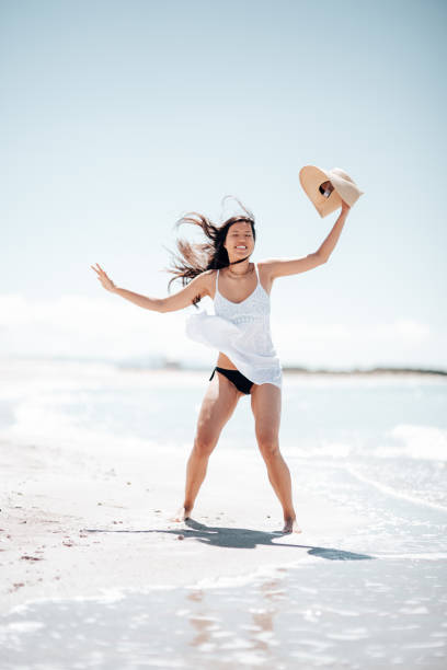 istock asian woman jumping on the beach 1390038821
