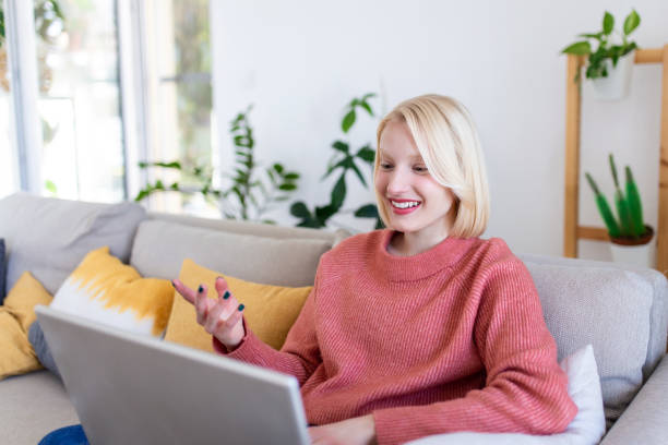 istock Smiling young woman using laptop at home, looking at screen, chatting, wearing wireless headset having video conference . business trainer tutoring by webcam, online training, e-coaching concept 1390040309