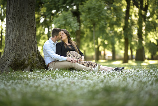 Shot of a young expecting couple posing together in the park