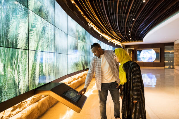 touristes utilisant la technologie dans le centre des visiteurs d’at-turaif - écran vidéo photos et images de collection