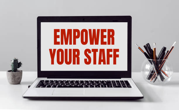 istock Laptop with EMPOWER YOUR STAFF text on modern office background. 1390041384