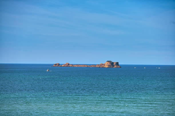 Saint-Malo, France, August 30, 2019: Looking at a old fortress in the front of city of Saint-Malo. The city is a historic French port in Ille-et-Vilaine, Brittany on the English Channel coast. The city had a long history of piracy, earning much wealth from local extortion and overseas adventures. The city changed into a popular tourist centre, with a ferry terminal serving the Channel Islands of Jersey and Guernsey, as well as the Southern English settlements of Portsmouth, Hampshire and Poole, Dorset.