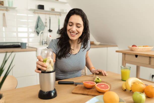 istock Happy young woman making a smoothie for snack 1390042986