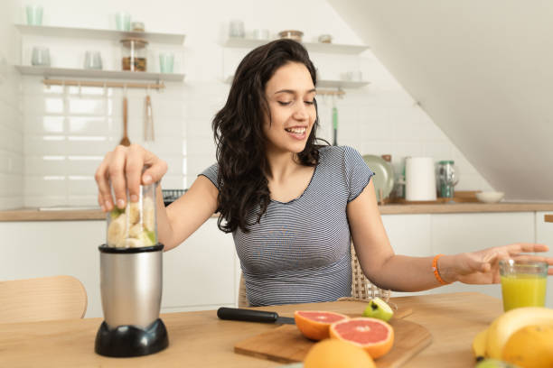 istock Happy girl using a blender to make a smoothie 1390042991