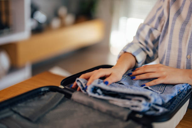istock Female with blue colored nails packing clothes. 1390043555