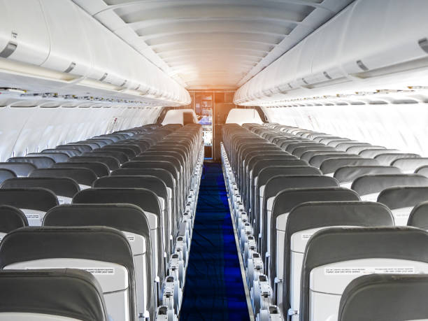 istock Passenger plane interior. Empty airplane interior with chairs and folding tables in seat back. Cabin of passenger aircraft, economy class or salon in jet. 1390044830