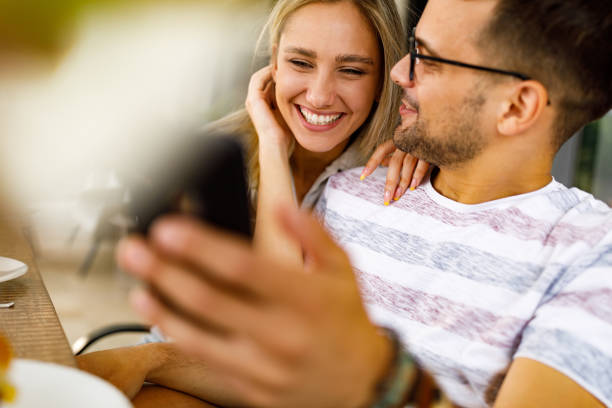 istock Young happy couple using cell phone on a patio. 1390045086