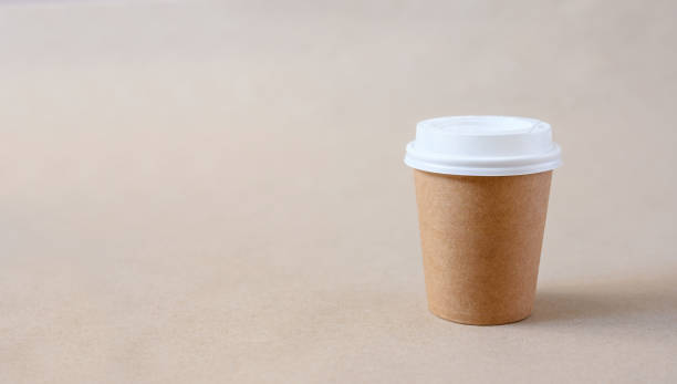 istock Paper disposable cup with white lid on craft paper background. 1390045348