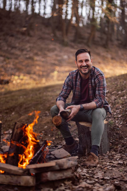 istock A man holding a log made a campfire, put bricks around the fire. 1390048516