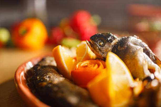 Salmon fillet seasoned with pepper and salt lies next to squeezed lemon on a stone stand