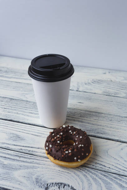 istock white glass with coffee on a light wooden background with donuts 1390053461