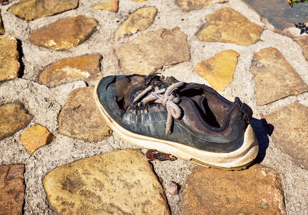 Forlorn damanged running shoe lying abandoned outdoors.
