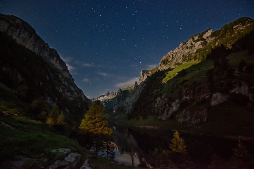 Lake Fählensee is one of three lakes in the Alpstein area of Appenzellerland. What looks here like the sun in the mountains is in fact the light of the full moon at midnight.