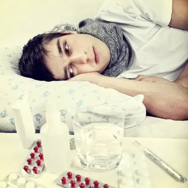 Toned Photo of Sad and Sick Young Man on the Bed
