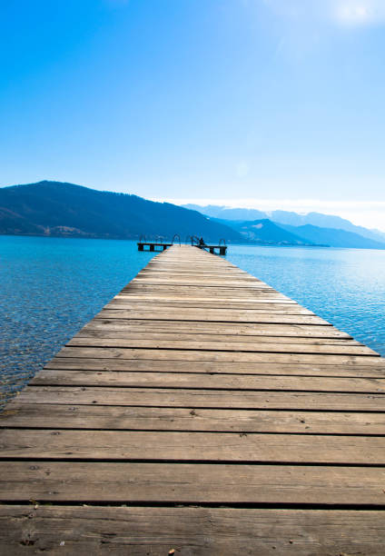 Jetty at Lake Attersee in Salzkammergut, Upper Austria Panoramic view of Lake Attersee with wooden pier and mountain range in the background. Salzkammergut Upper Austria attersee stock pictures, royalty-free photos & images