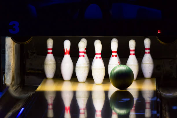 istock Bowling alley. Green bowling ball rolling into the pins 1390060633