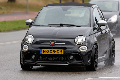 Enschede, Twente, Overijssel, Netherlands, april 5th 2022, daytime close-up of a Dutch black 2016 Abarth 500 on the 'Hengelosestraat' city street in Enschede on a rainy day - the Abarth 500 model is an exclusive tuned version of the Fiat 500 made by Italian, Turin based car manufacturer Abarth & C. S.p.A. since 2008
