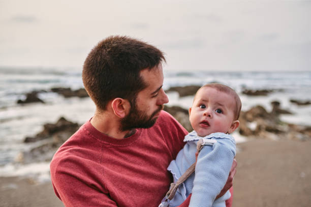 istock Young single father hugging his baby son on the beach 1390064643