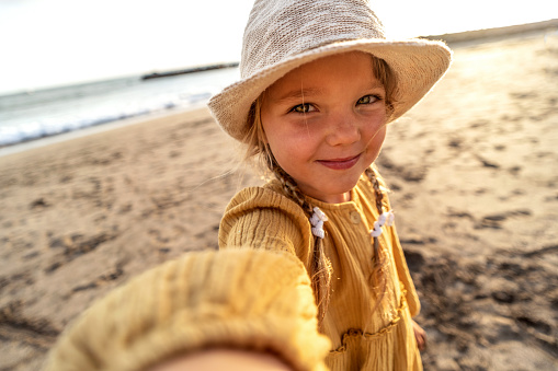 Happy little girl in hat taking selfie at tropical beach on Tenerife island during summer vacation. Travel. Tourism.