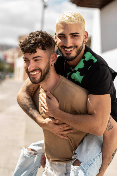 portret szczęśliwej pary gejów bawiących się na randce na świeżym powietrzu, bawiących się razem, uśmiechających się. prawdziwe emocje ludzi. - gay man couple lifestyles homosexual zdjęcia i obrazy z banku zdjęć