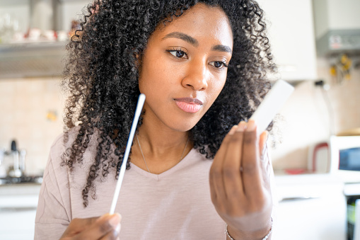 Una mujer negra haciéndose la prueba de coronavirus en casa photo