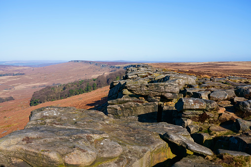 Weathered gritstone rocks along the top of Stanage Edge on a misty cloudless morning.