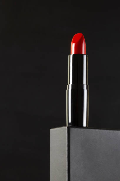 istock Red lipstick on gray stand podium on black background. Makeup. Copy space vertical layout 1390076143