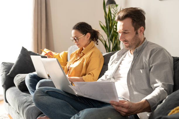 istock Couple using laptops for remote work on the sofa at home 1390080495