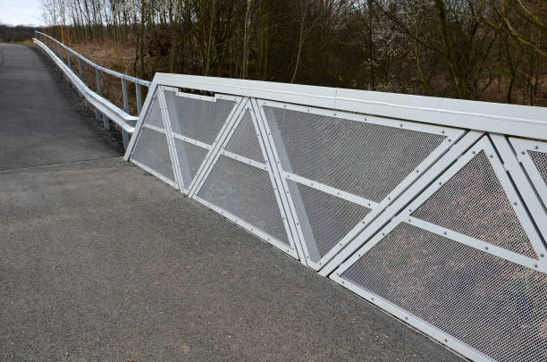 istock path for cyclists with an asphalt surface. galvanized iron railing over road barriers. Bridge railing with tilting to the sides. railing made of perforated sheet metal in the shape of a triangle 1390086613