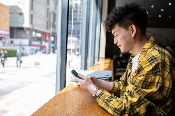 istock Asian handsome young man using smartphone in coffee shop 1390086886