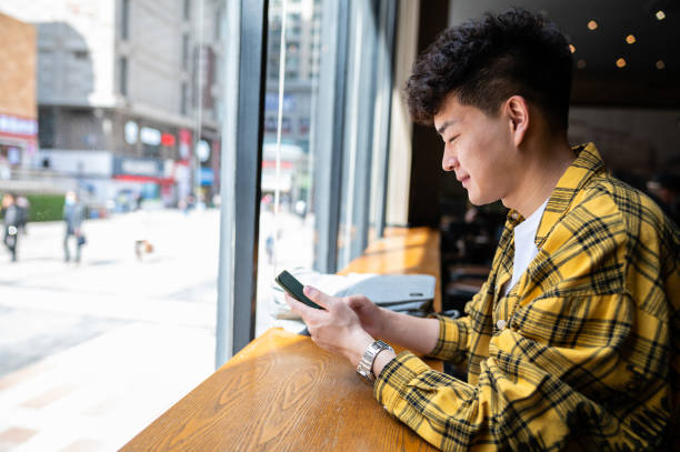 Asian handsome young man using smartphone in coffee shop Asian handsome young man using smartphone in coffee shop Best Student Apps stock pictures, royalty-free photos & images