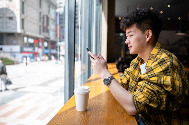 istock Asian handsome young man using smartphone in coffee shop 1390087189