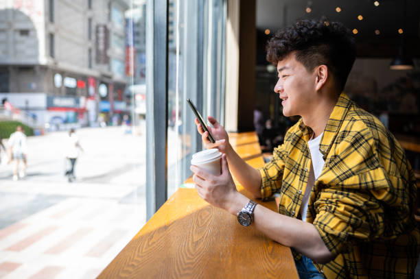 istock Asian handsome young man using smartphone in coffee shop 1390087323