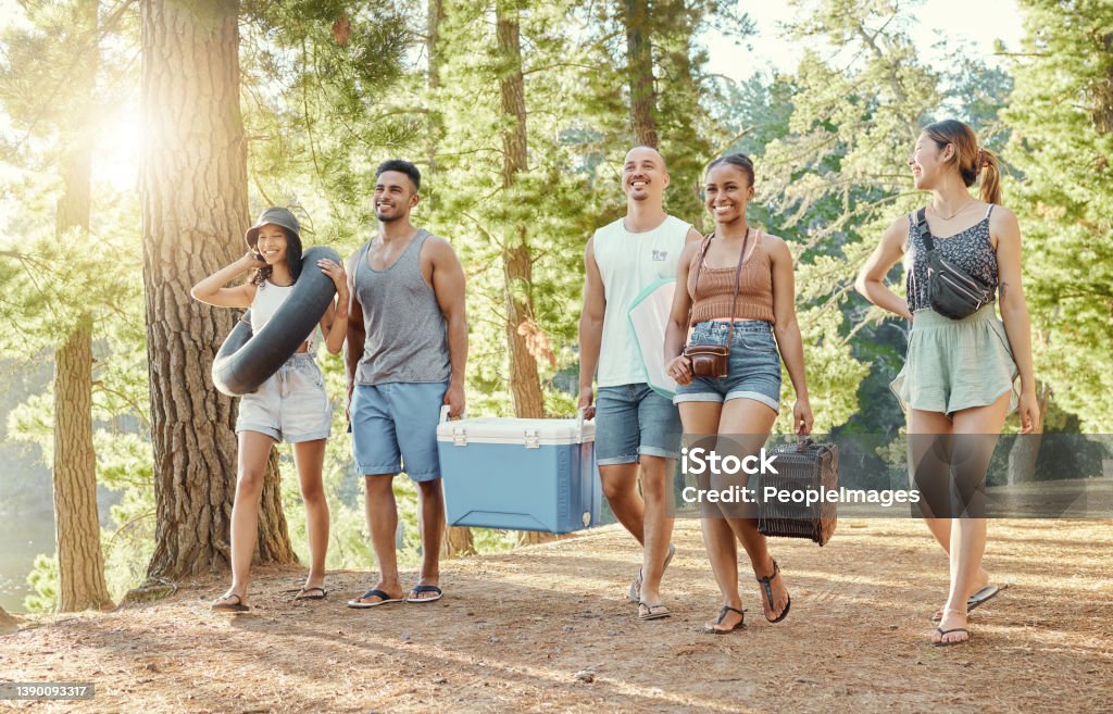 Full length shot of a diverse group of friends enjoying a day out in the woods Where should we set up? Cooler - Container Stock Photo
