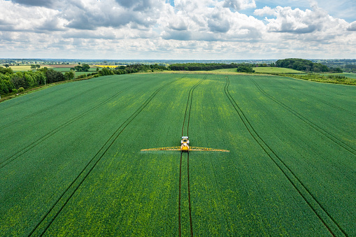 Aerial view of farming tractor crop sprayer in the countryside