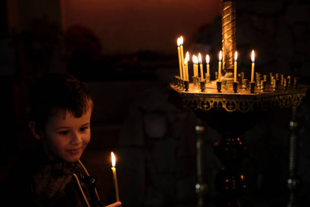 istock Little boy holding candle on dark background. 1390094657