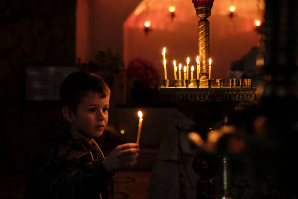 istock Little boy holding candle on dark background. 1390094658